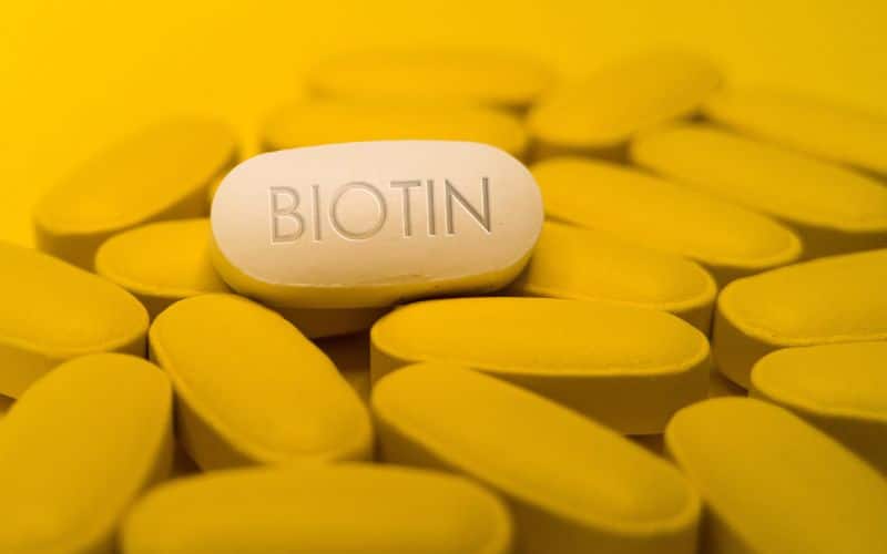 Biotin vitamin B7 white pill tablet on yellow background is vitamin involved in metabolic processes