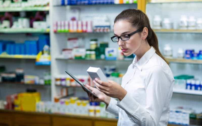 Pharmacist using digital tablet while checking medicine in pharmacy